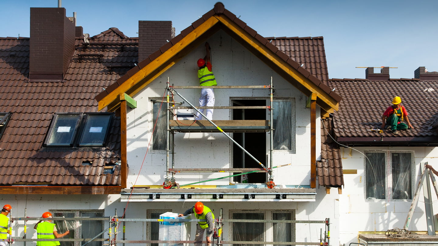 Bauarbeiter renovieren ein altes Haus – Fassadenarbeiten und Dachsanierung im Gange