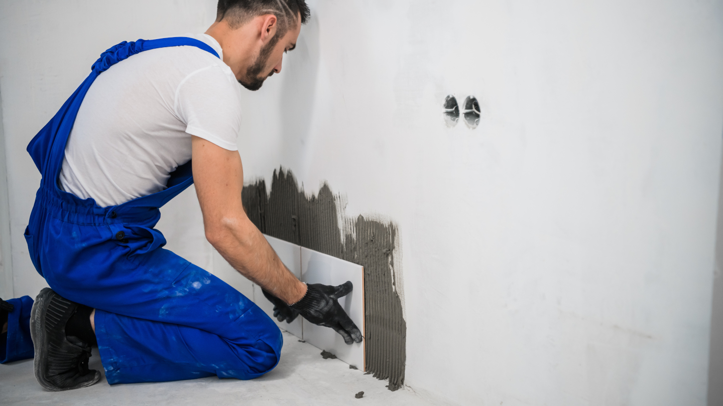 Fliesenleger bei der Arbeit – er verlegt Wandfliesen in einem Innenraum